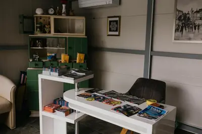 a room with a table with books and a chair at Apartments Drevi in Ljubljana