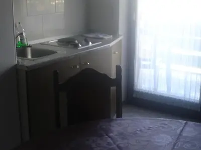 a kitchen with a sink and a table with a chair at Tiffany Pension Bled in Bled