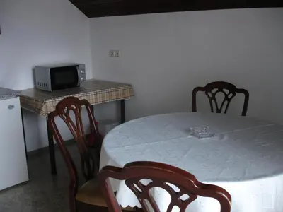 a room with a table with a microwave and a table with chairs at Tiffany Pension Bled in Bled
