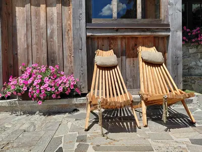 two chairs sitting in front of a building with flowers at Apartma Alpski vrt in Vojsko
