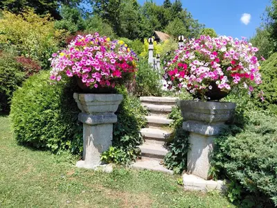 a garden with two stone vases filled with flowers at Apartma Alpski vrt in Vojsko