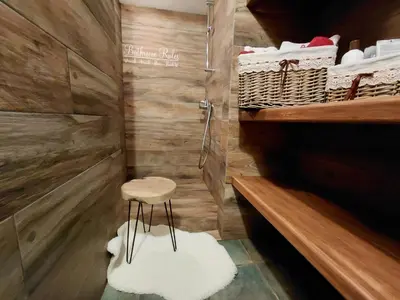 a bathroom with a stool and a shower with towels at Apartma Alpski vrt in Vojsko