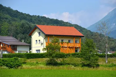 a house with an orange roof in front of a mountain at HišaŠmihelka in Kobarid