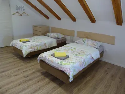 two beds in a room with wooden floors at HišaŠmihelka in Kobarid