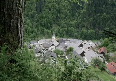 a group of houses in a valley with a church at Village House in Železniki