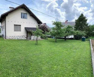 a white house with a yard with trees in front of it at House Amalia in Bled