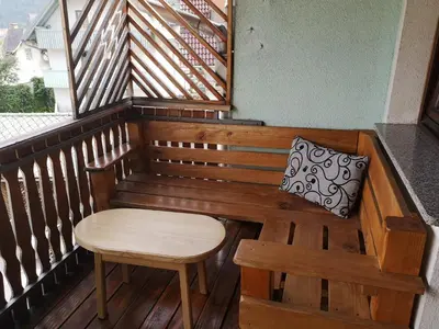 a wooden bench with a table and a pillow on a balcony at Sobe SM0LEJ in Bled