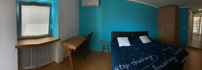 a bedroom with blue walls and a bed and a desk at Mr and Mrs Bright 5 in Ljubljana