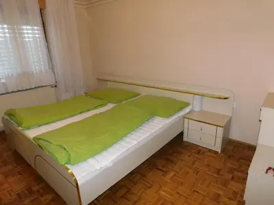 a bedroom with a bed with green sheets and a table at Haus Videm in Videm pri Ptuju