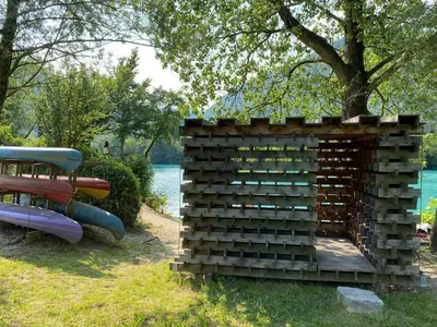 a wooden structure in the grass next to a bench at Apartma Leban Most na Soči in Most na Soči