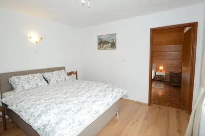 a white bedroom with a bed and a wooden floor at Brane & Jaka Apartments in Bohinj