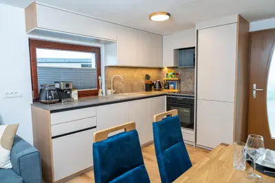 a kitchen with a table and blue chairs in a room at Brane & Jaka Apartments in Bohinj
