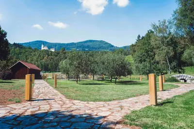 a stone path in a field with a barn and trees at Apartments Kamp Podgrad Vransko in Vransko