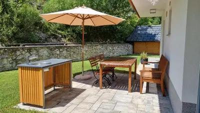 a patio with an umbrella and a table and chairs at Apartments Vila Darja in Bohinj