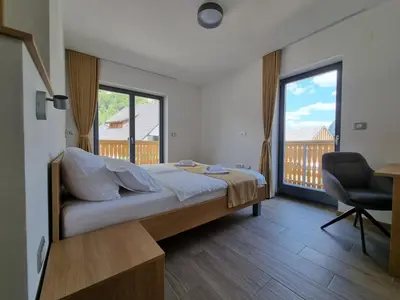 a bedroom with a bed and a desk and a window at Apartments Vila Darja in Bohinj