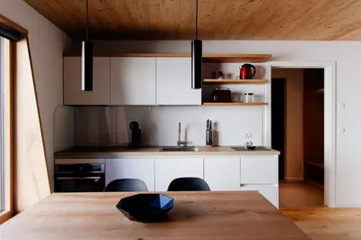 a kitchen with white cabinets and a wooden ceiling at Apartmaji štAla in Kranjska Gora