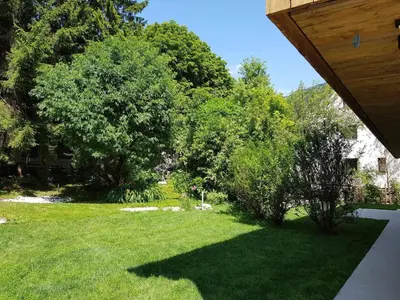 a yard with green grass and trees and a house at Apartmaji štAla in Kranjska Gora