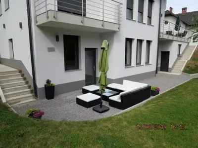 a patio with a green umbrella and chairs and a building at Sunlight Apartment in Bled