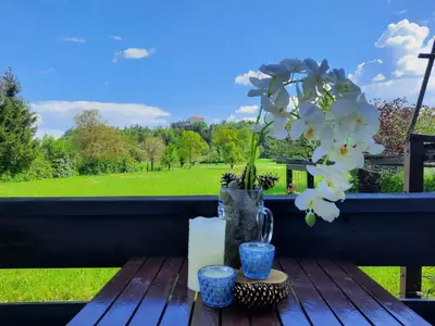 a table with a vase with flowers and a window at Deerwood Holiday Cozy Retreat 2br Apartment with Stunning Castle Views in Bled
