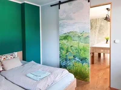a bedroom with a bed and a painting on the wall at Deerwood Holiday Cozy Retreat 2br Apartment with Stunning Castle Views in Bled