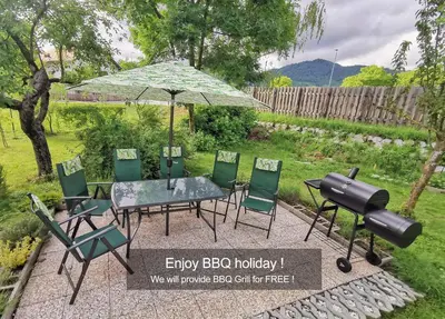 a table and chairs with an umbrella and a grill at Deerwood Holiday Cozy Retreat 2br Apartment with Stunning Castle Views in Bled