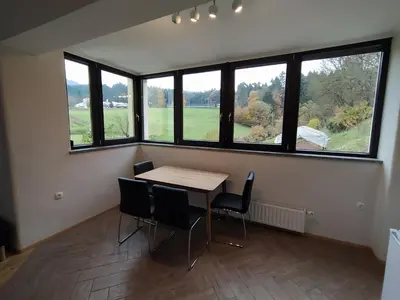 a room with a table and chairs and windows at Apartmaji Maln in Dolenjske Toplice