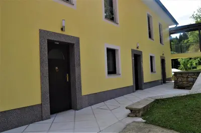 a yellow building with a black door and a sidewalk at Apartmaji Maln in Dolenjske Toplice