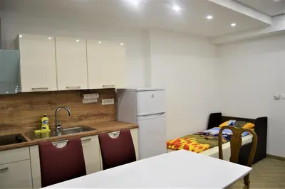 a kitchen with white cabinets and a sink and a table at Apartmaji Maln in Dolenjske Toplice