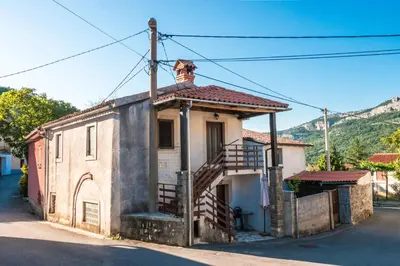 an old house with a staircase on a street at Hiša Hrastovlje - Countryside House in Hrastovlje