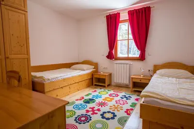 a small bedroom with two beds and a rug at Bolfenk lodge apartment in Pohorje