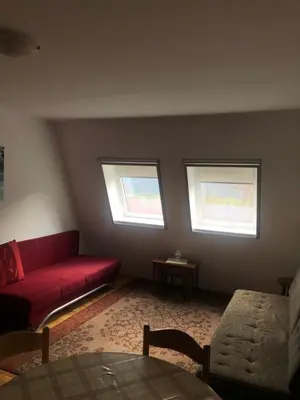 a living room with a red couch and two windows at Retro apartments Kaninska vas in Bovec