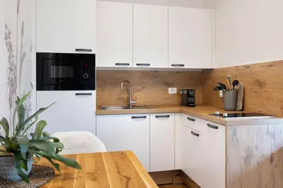 a kitchen with white cabinets and a wooden table at Hiša Vally Art in Bled