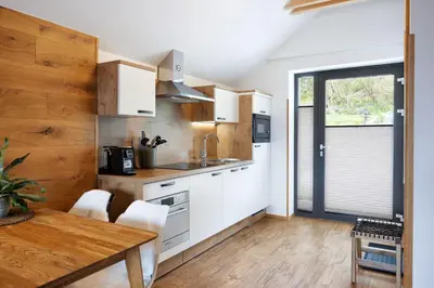 a kitchen with white cabinets and a table and a window at Hiša Vally Art in Bled