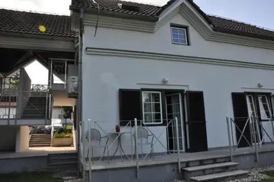 a white house with two chairs on the porch at Vas Lipa 7 -30 in Podčetrtek