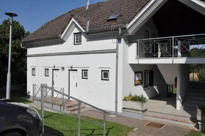 a white house with a garage and a balcony at Vas Lipa 7 -30 in Podčetrtek