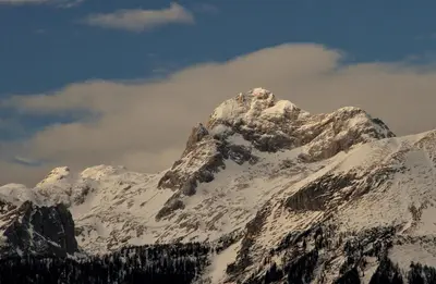 a mountain covered in snow with a cloudy sky at Apartmaji Alpski cvet - Hiša Gorenc in Bohinj