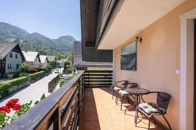 a balcony of a house with chairs and a table at Apartmaji Alpski cvet - Hiša Gorenc in Bohinj