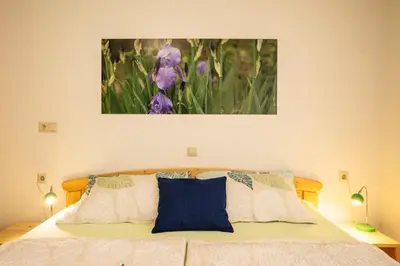 a bedroom with a bed with purple flowers on it at Apartmaji Alpski cvet - Hiša Gorenc in Bohinj