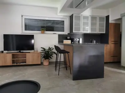 a kitchen with a bar with a tv and a bar stool at Brand new house Luna in Bled