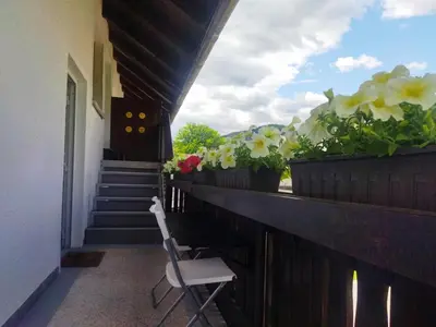 a chair sitting on a balcony with flowers at Apartma Vojvoda in Bohinj