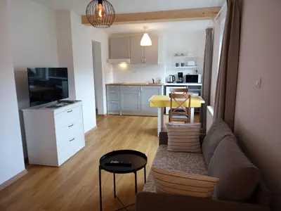a living room with a couch and a table and a kitchen at Apartma Vojvoda in Bohinj