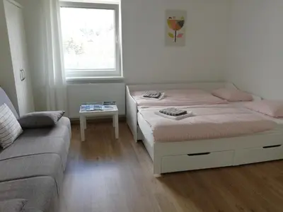 two beds in a room with a couch and a window at Apartma Vojvoda in Bohinj