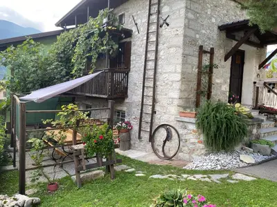 a stone house with a balcony and flowers in the yard at Apartma Skednj in Kobarid