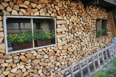 a building with two windows and a pile of wood at Apartma Skednj in Kobarid