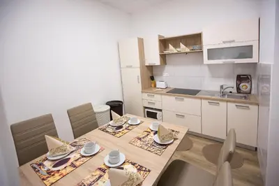 a kitchen with a wooden table and chairs and a kitchen with white cabinets at MINIDORM ROOMS IN HEART OF CITY CENTER in Maribor