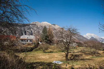 a house in a field in front of a mountain at Apartma Rombon Brdo with Free Onsite Parking in Bovec