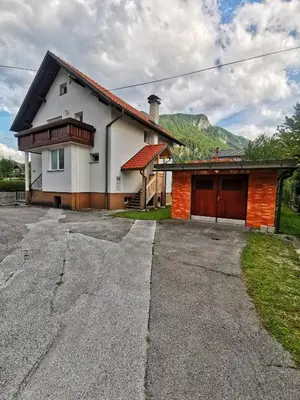 a house with a garage and mountains in the background at Apartmaji Tomšič in Mojstrana
