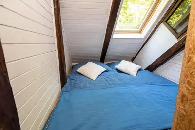a bed in a tiny house with two pillows at Apartma waterfall Slap in Bohinj