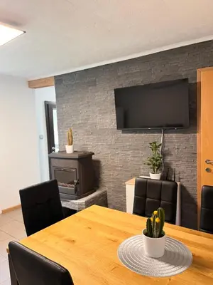 a dining room with a table and a television on a brick wall at APARTMA BENY with SAUNA in Žaga