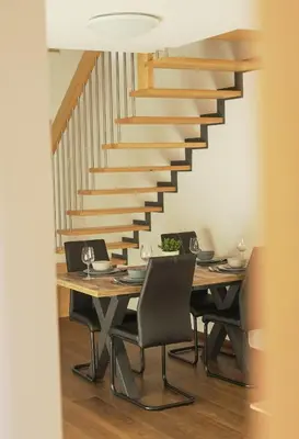 a dining room with a table and a staircase at Ski and Bike Apartment Rušovc in Kranjska Gora